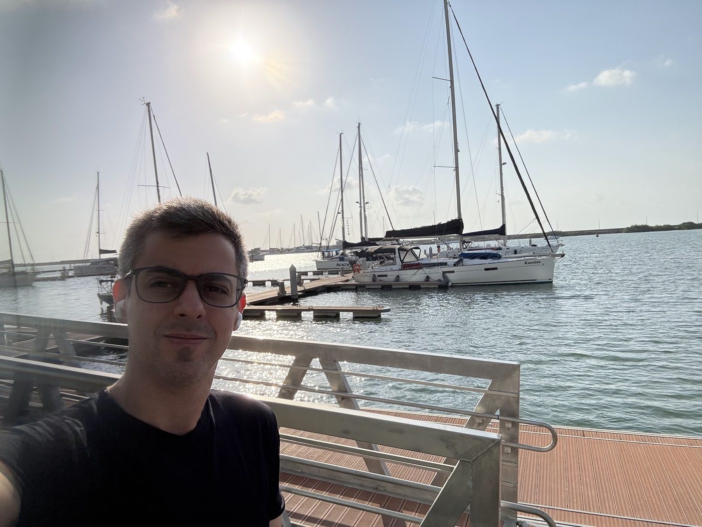 Rodrigo Krüger on the waterfront at Cais de Santa Rita in Recife, with moored sailing boats and the river behind him.